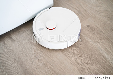 Top view of robot vacuum cleaner on wooden floor, smart home cleaning device with lidar sensor and modern minimalist interior Top view of robot vacuum cleaner on wooden floor, smart home cleaning device with lidar sensor and modern minimalist interior 135373164