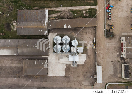 Top-down drone view of agricultural grain elevator with storage silos, conveyors and warehouses in an industrial farm complex 135373239