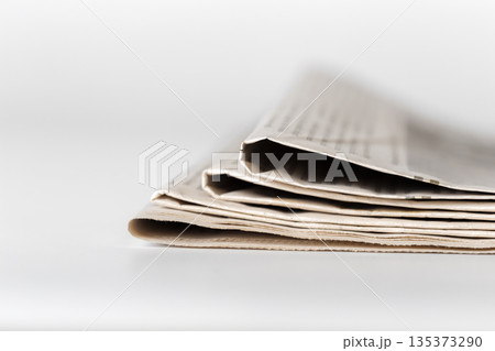 Newspaper folded on a table with printed text and clear background lighting Newspaper folded on a table with printed text and clear background lighting 135373290