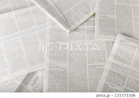 Collection of printed newspapers arranged in a scattered layout on a flat surface 135373306