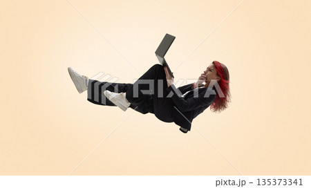 Freelancer working remotely on laptop in relaxed floating position. Freelancer working remotely on laptop in relaxed floating position. 135373341