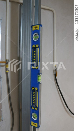 Measuring the vertical of profiled metal built into a room structure using a level tool magnetized to an iron guide, constructing a metal frame in a technical room and checking the angle 135373507