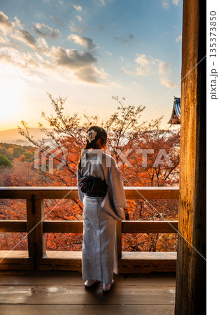 Unknown tourist with kimono outfit standing on the wooden walkway inside Kiyomizu-dera building. 135373850