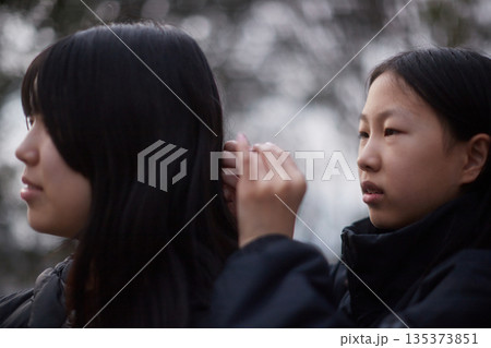 冬の公園でお姉さんの白髪をチェックする可愛い女の子の様子 135373851