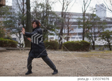 冬の住宅地の公園で太極拳を練習する中年女性主婦の姿 135374076
