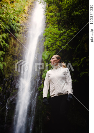 Solo trekker stands quietly beneath lush green canopy while contemplating Solo trekker stands quietly beneath lush green canopy while contemplating 135374339
