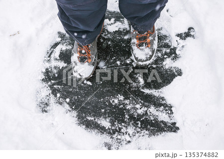 Winter Ice Hazard -Man in Boots on Slippery Frozen Lake 135374882
