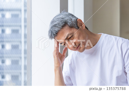 窓辺で頭を抱えるシニア男性 135375788