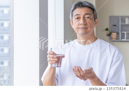 窓辺で薬を飲むシニア男性 135375814