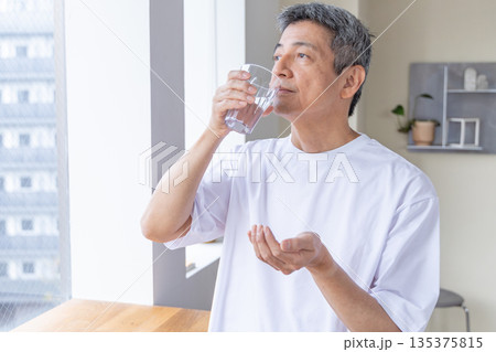 窓辺で薬を飲むシニア男性 135375815