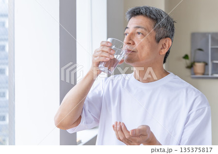 窓辺で薬を飲むシニア男性 135375817