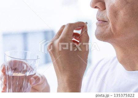 窓辺で薬を飲むシニア男性 135375822