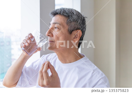 窓辺で薬を飲むシニア男性 135375823