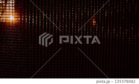 vibrant sunset rays piercing dark chain link fence mesh in urban twilight evoking mystery and intrigue for atmospheric wallpaper or banner with copy space vibrant sunset rays piercing dark chain link fence mesh in urban twilight evoking mystery and intrigue for atmospheric wallpaper or banner with copy space 135376082