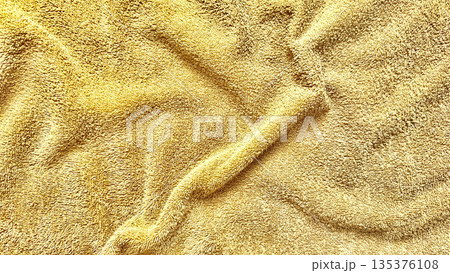 golden terry cloth texture folds in soft luxurious waves closeup for spa wellness wallpaper or commercial bath background 135376108
