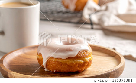 木製プレートに乗ったグレーズドーナツとコーヒー・おやつの時間 135376391