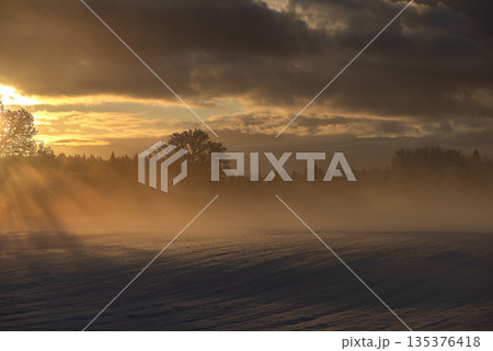 Warm Sunset Fog Over Frozen Winter Field 135376418