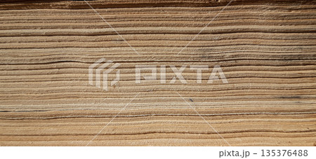 Textured layers of aged book pages. A close-up of the page edges of an old book, showing a series of horizontal lines created by the layered sheets. 135376488