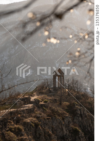 Stone watchtower of Harsnadzor standing on rocky hill in winter, framed by bare tree branches with soft bokeh, dramatic mountain gorge in background Stone watchtower of Harsnadzor standing on rocky hill in winter, framed by bare tree branches with soft bokeh, dramatic mountain gorge in background 135376850