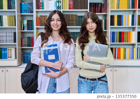 Portrait of two teenage students classmates looking at camera in classroom library 135377350