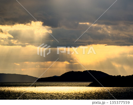 天使の梯子が降り注ぐ夕景の海と島影 天使の梯子が降り注ぐ夕景の海と島影 135377559