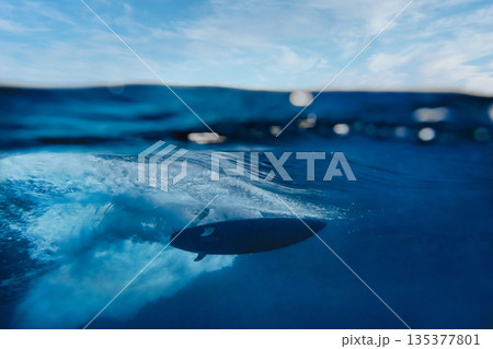Underwater perspective of surfing through blue depths Underwater perspective of surfing through blue depths 135377801