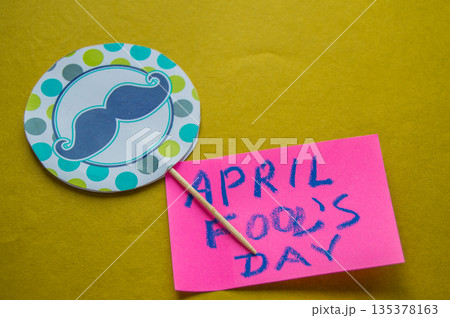 Paper topper with a painted mustache and the words April fool's day, yellow background 135378163