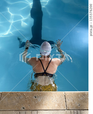 Woman Swims Laps in Pool for Exercise Routine Woman Swims Laps in Pool for Exercise Routine 135378200
