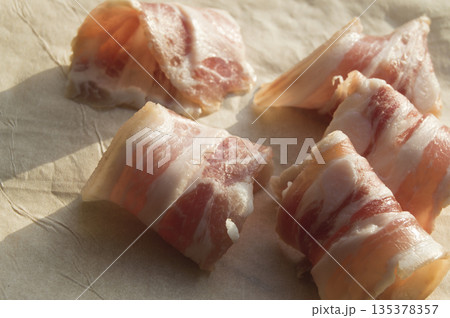Slices of bacon are rolled into the rolls on parchment 135378357