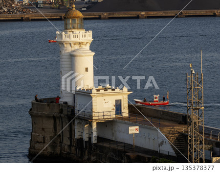 East Breakwater Lighthouse in Port of Bilbao with a Small Boat Passing 135378377