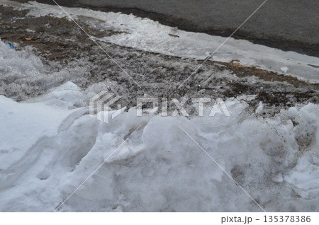 Spring background is a dirty loose snow melting outdoors 135378386
