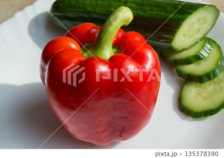 Delicious red pepper and sliced cucumber on a white plate 135378390