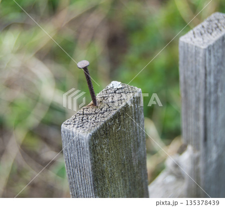 Old wooden fence and a rusty nail sticking out 135378439