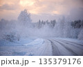 Curving Winter Road Through Frosty Forest and Light Fog in Latvia 135379176