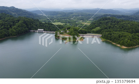 ダム湖と堤体、緑の山並みを望む空撮風景 ダム湖と堤体、緑の山並みを望む空撮風景 135379694