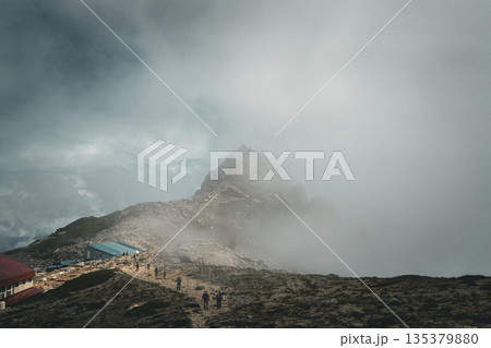 霧に包まれた稜線の登山道と山小屋の風景 霧に包まれた稜線の登山道と山小屋の風景 135379880