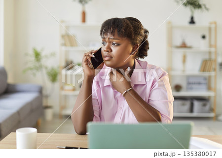 Worried african american woman talking on smartphone 135380017