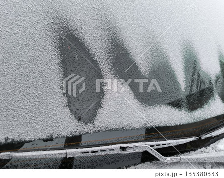 The frozen windshield of the car begins to thaw, frozen wiper blades The frozen windshield of the car begins to thaw, frozen wiper blades 135380333