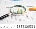 Magnifying glass on spreadsheet and graph paper. 135380531