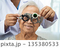Asian senior woman wearing ophthalmic vision eye test and using optical trial frame. 135380533