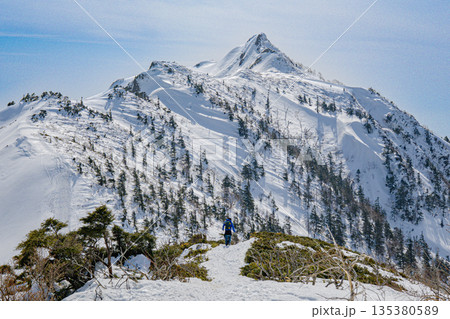 雪稜を進む登山者と迫力の冬山稜線 雪稜を進む登山者と迫力の冬山稜線 135380589