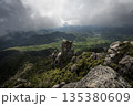 雲間の光が差す岩峰と新緑の山並み 135380609