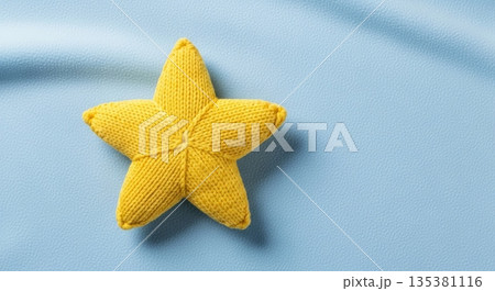 Cute yellow knitted star on soft blue fabric background for baby nursery decor 135381116