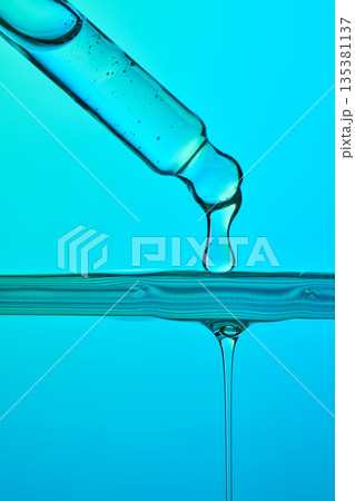 Pipette dispensing blue serum droplet into clear liquid Pipette dispensing blue serum droplet into clear liquid 135381137