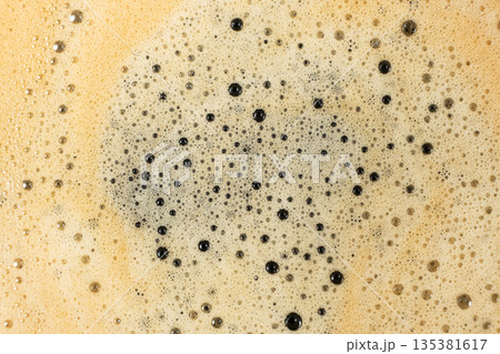 Macro texture of golden coffee foam with many small bubbles. 135381617