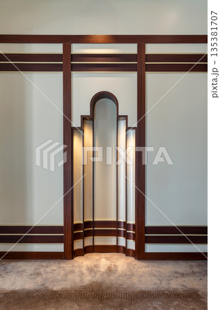 Art Deco architectural detail with arched niche, illuminated panels, dark wood, and gold accents. 135381707