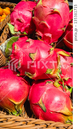 Vibrant pink dragon fruits or pitaya in a wicker basket at a local tropical fruit market or grocery 135381715