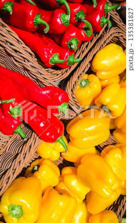 Fresh red and yellow bell peppers organized in wicker baskets at a local market or grocery store Fresh red and yellow bell peppers organized in wicker baskets at a local market or grocery store 135381827
