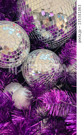 Close-up of sparkling silver disco balls and purple tinsel decorations for a festive holiday party 135381863