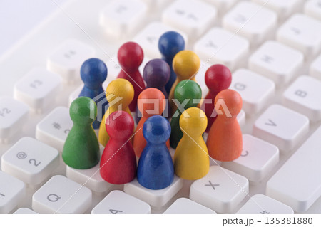 Colorful group of pawn people figures on computer keyboard Colorful group of pawn people figures on computer keyboard 135381880